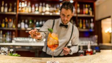 A bartender preparing a cocktail with a mint garnish.