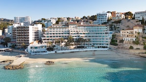 A coastal hotel with multiple floors, balconies, and a beach view.