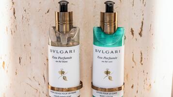 Two bottles of BVLGARI Eau Parfumée against a textured wall.