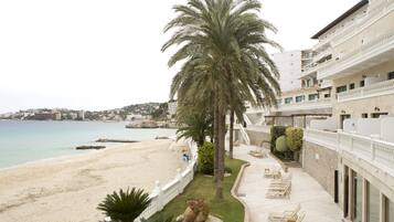 Hotel frente al mar con una palmera, playa y vista al océano.
