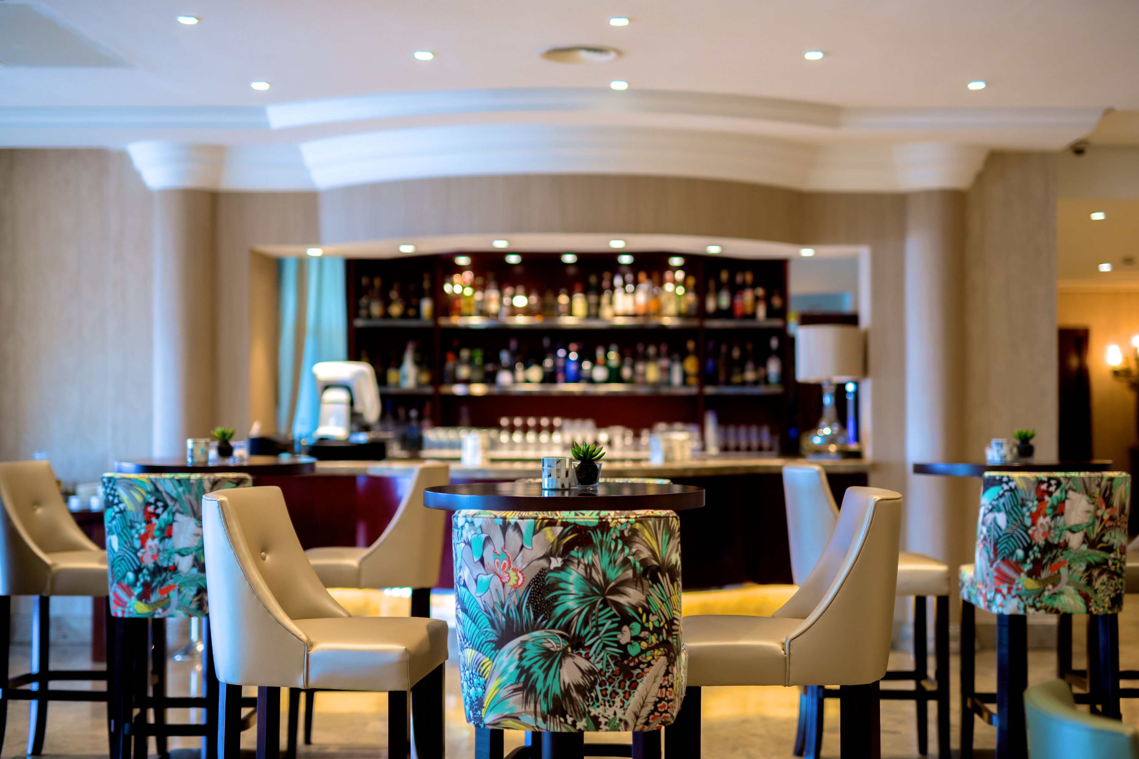 A bar area with a bar counter and multiple chairs with floral upholstery.