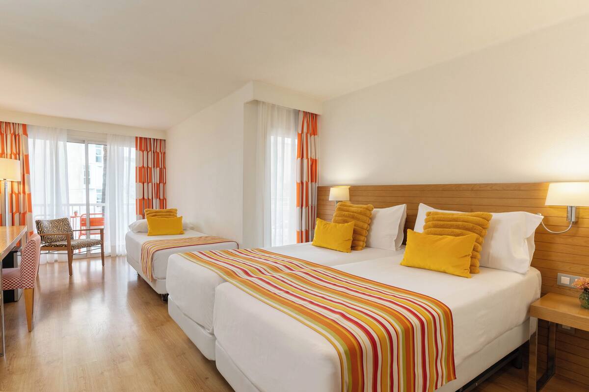 A hotel room with two beds, a desk, and a chair.