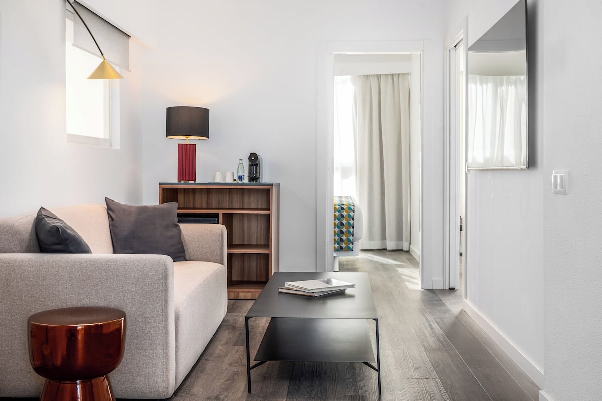 A modern living room with a sofa, a coffee table, a lamp, and a bookshelf.