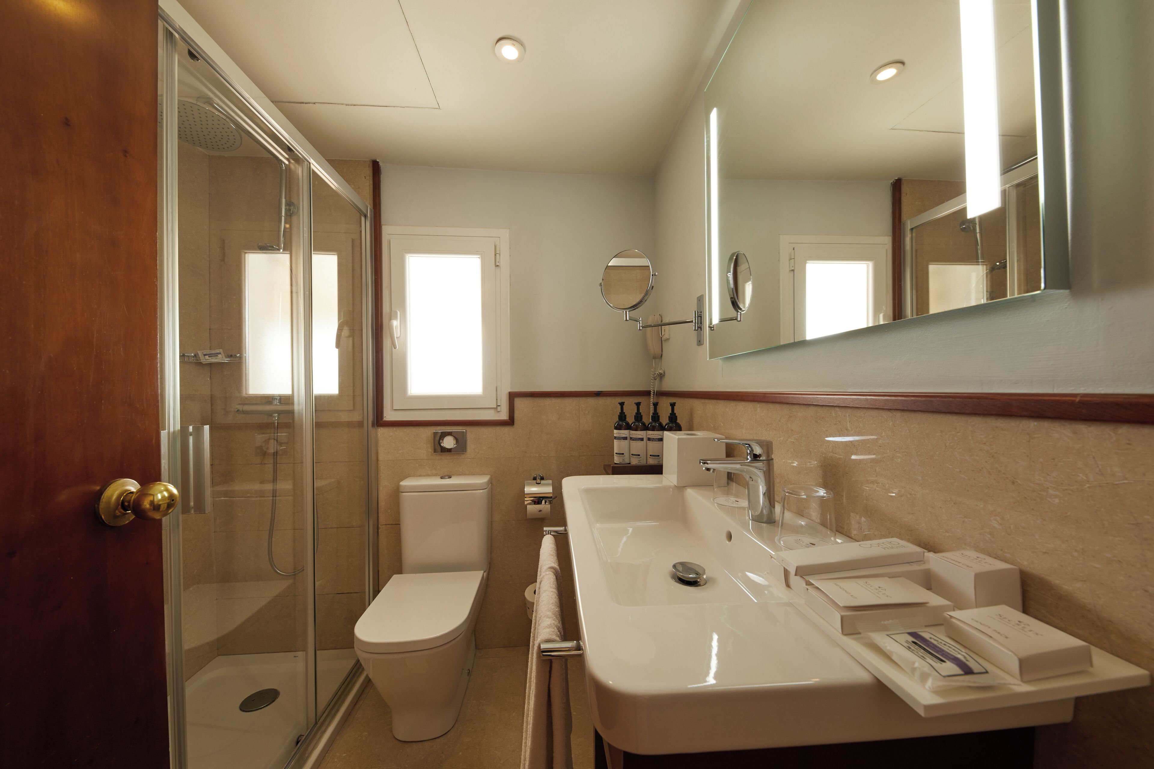 Une salle de bain moderne avec une douche à parois de verre, des toilettes blanches et un grand lavabo agrémenté d’articles de toilette.