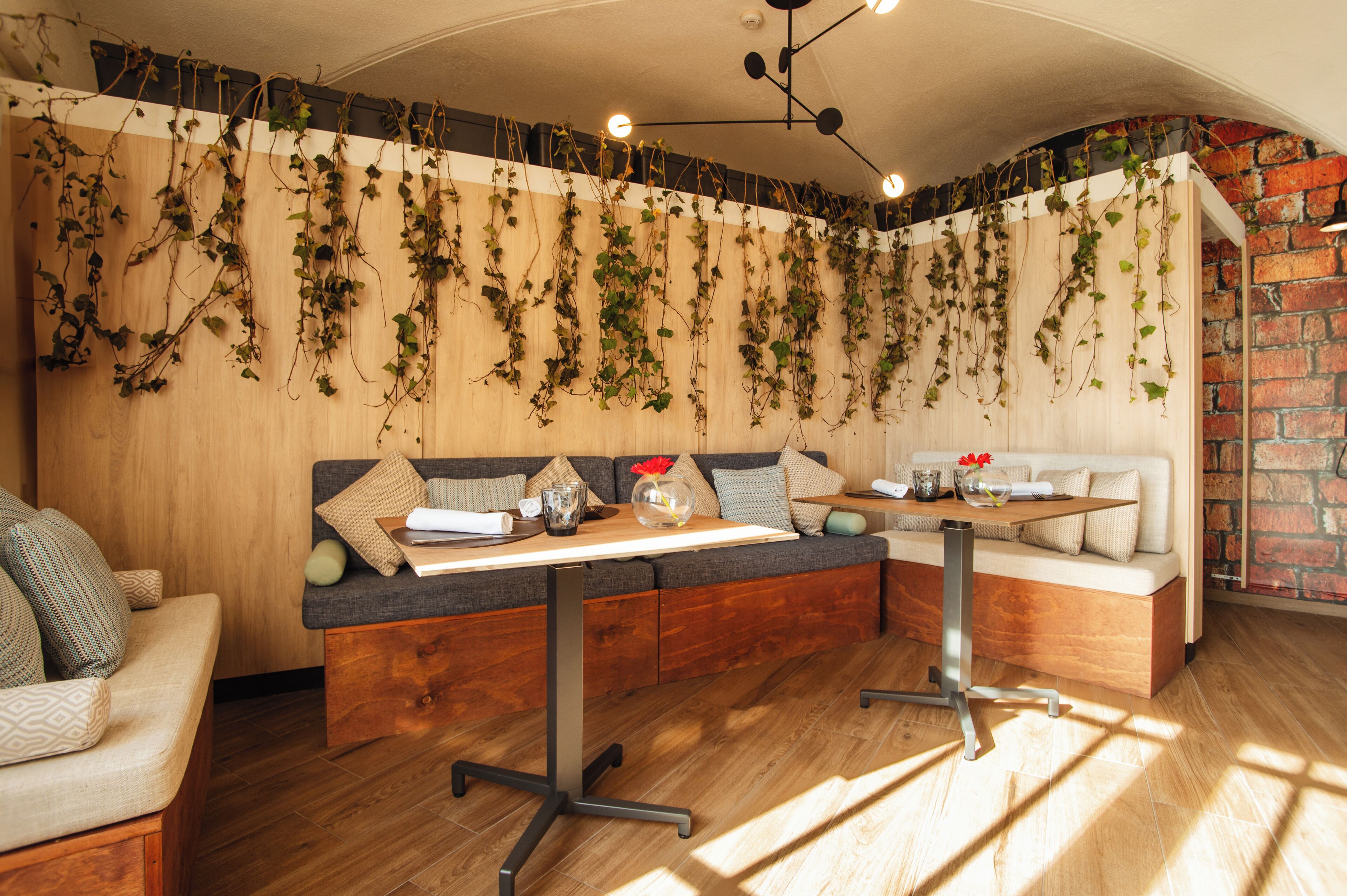 A cozy seating area with a wooden bench and a table, surrounded by brick walls and a wooden floor.