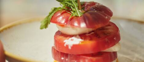 A plate with a layered food item, possibly a sandwich or appetizer, held by a person.