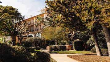 Un bâtiment à la façade incurvée, entouré de jardins bien entretenus et de palmiers.