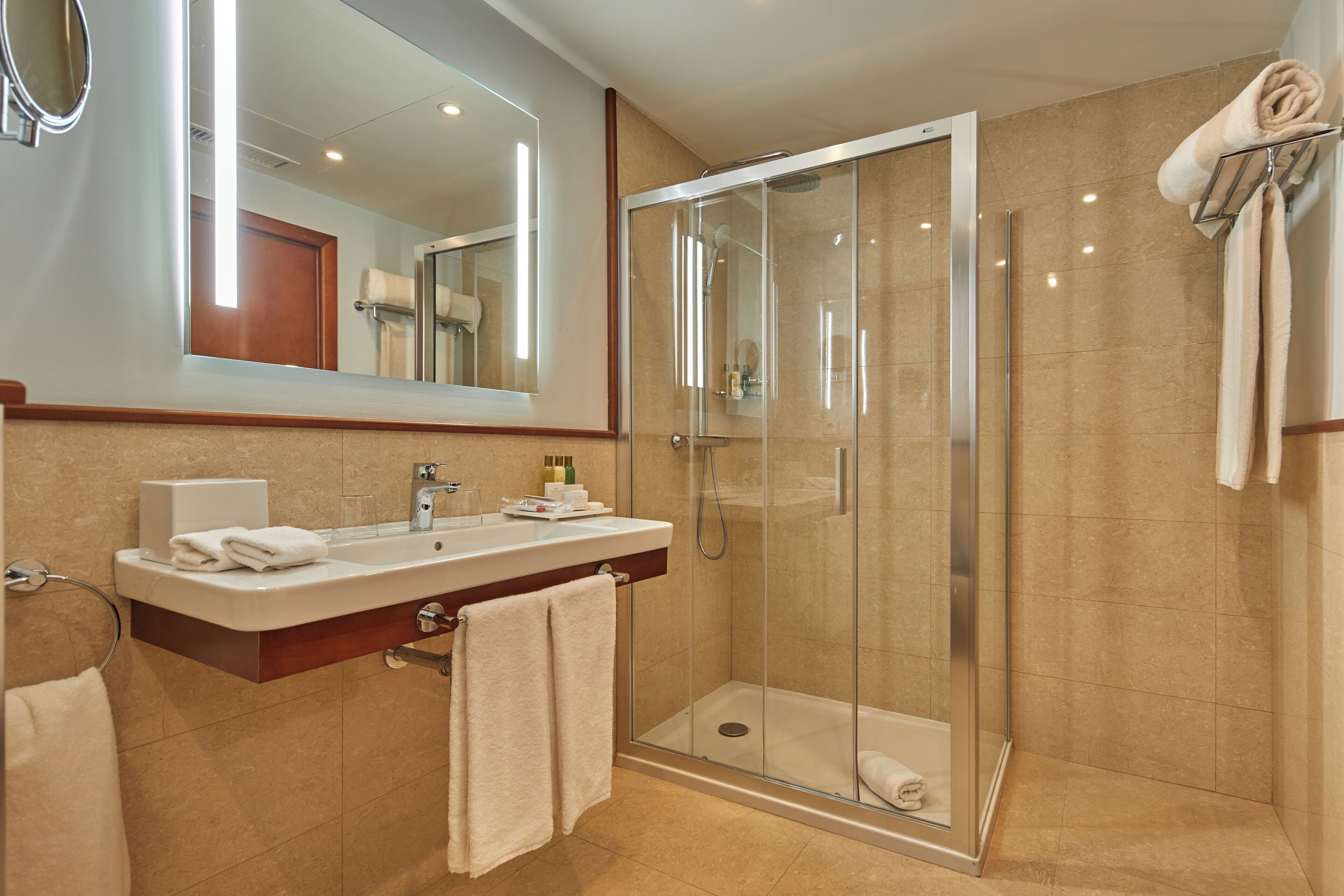 A modern bathroom with a glass-enclosed shower, a vanity with a mirror, and a towel rack.