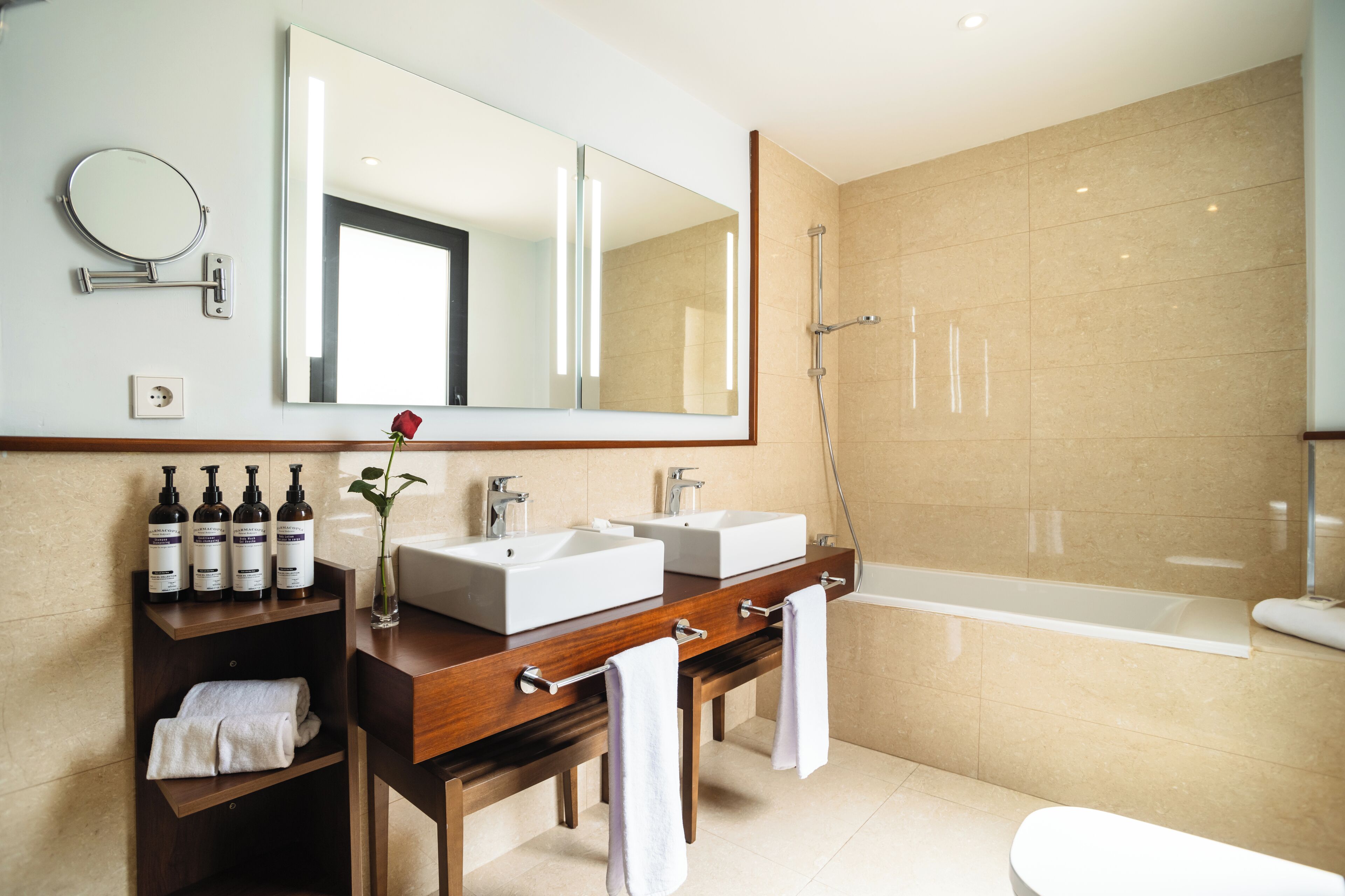 Un baño moderno con un espejo grande, dos lavamanos, una ducha y un inodoro.