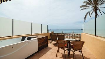 A sunlit outdoor area with a pool, chairs, and a view of the sea.