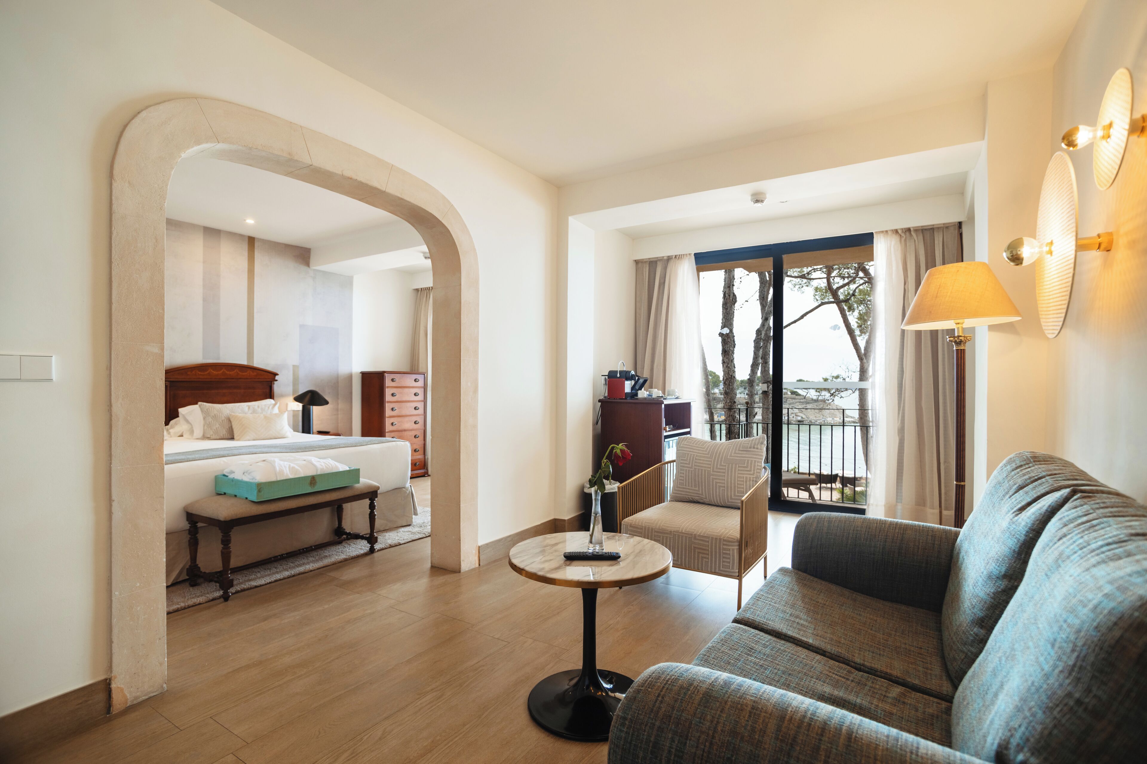 Habitación de hotel con cama, sofá, una mesita y balcón con vistas.