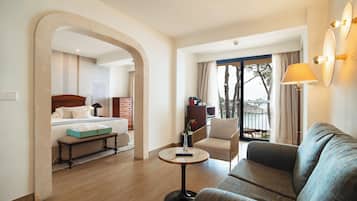 Habitación de hotel con cama, sofá, una mesita y balcón con vistas.