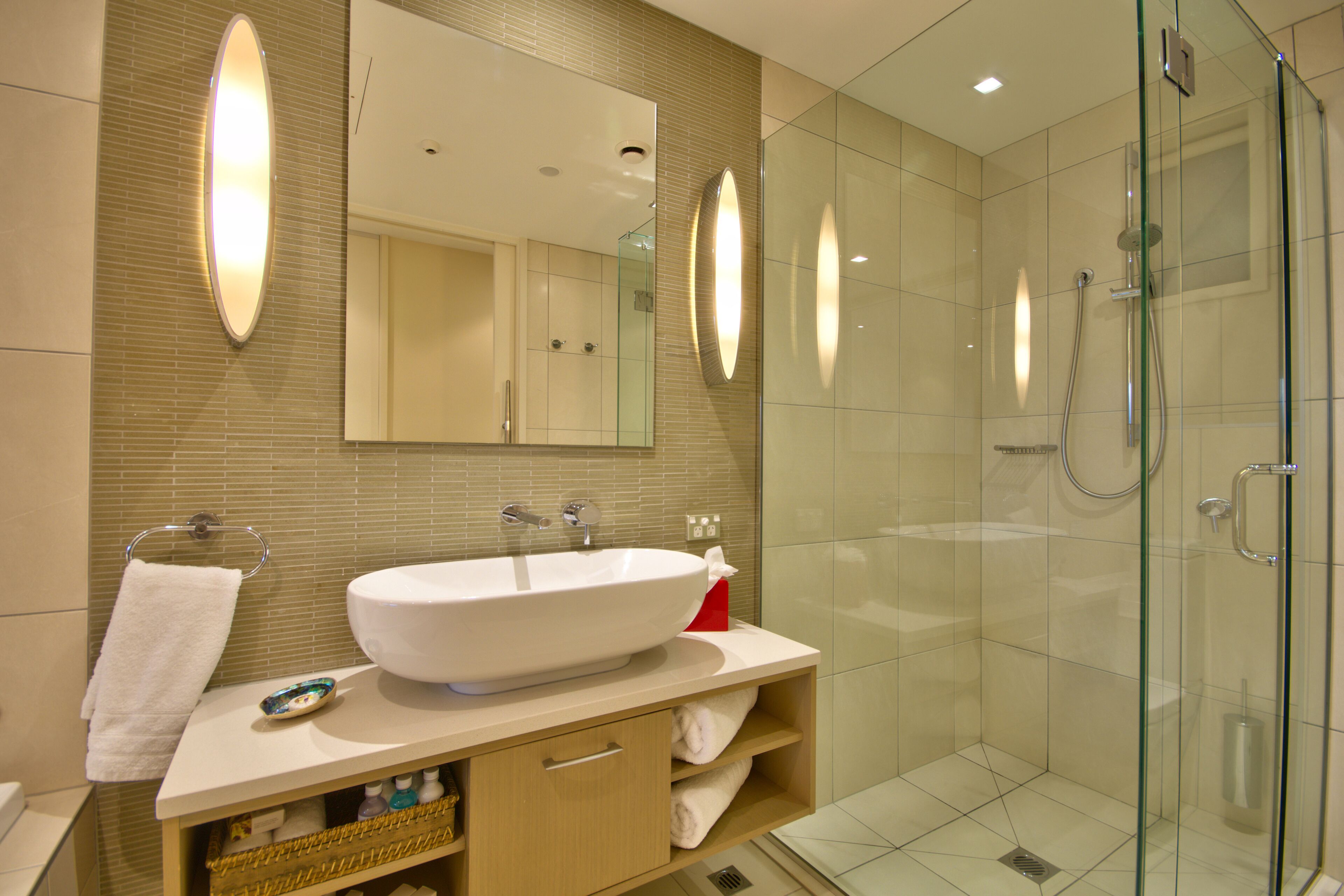 A modern bathroom with a large oval sink, a glass-enclosed shower, and a mirror above the sink.