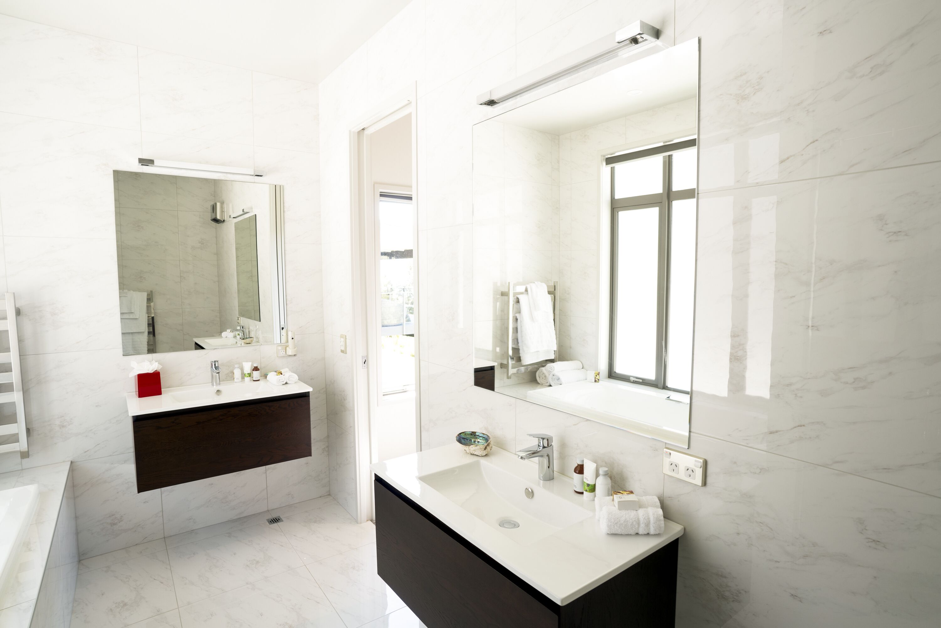 A modern bathroom with a large mirror, a vanity with a sink, and a bathtub.