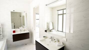 A modern bathroom with a large mirror, a vanity with a sink, and a bathtub.