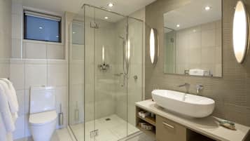 A modern bathroom with a glass-enclosed shower, a large mirror, and a white sink.