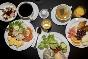 A breakfast table with various dishes including eggs, toast, smoked salmon, and fruit. - Hotel Noreg (Ålesund)