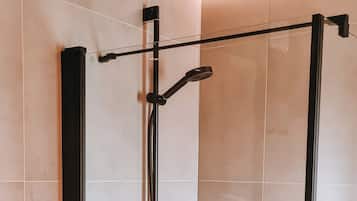 A modern shower enclosure with a control panel and a handheld showerhead.