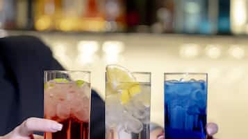 Tres vasos de bebidas con hielo y adornos, sostenidos por manos.