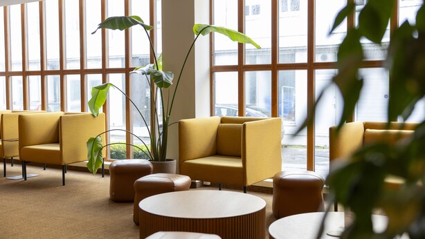A modern waiting area with yellow sofas, round tables, and potted plants. - Hotel Noreg (Ålesund)