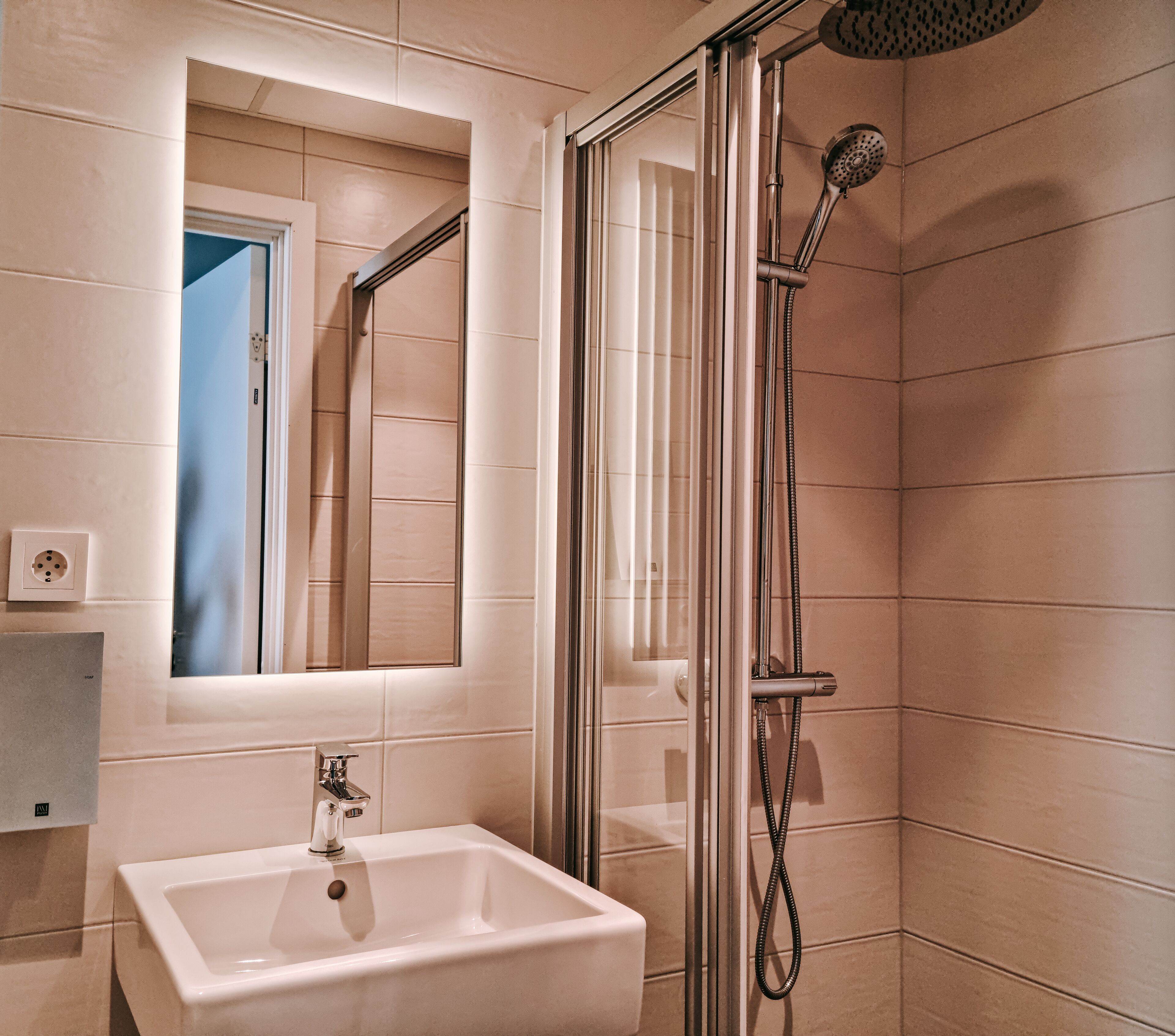 A modern bathroom with a glass-enclosed shower, a sink, and a mirror.