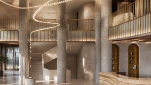 Um hall amplo com uma escadaria espiral central, colunas imponentes e um balcão de recepção.