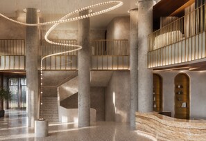 A spacious lobby with a central spiral staircase, large columns, and a reception desk.