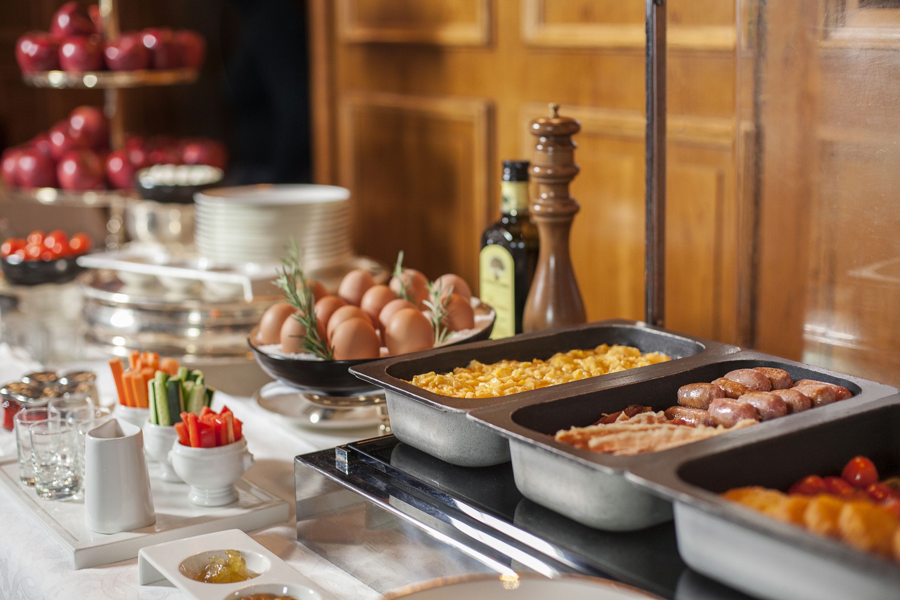 Ein reichhaltiges Buffet mit verschiedenen Speisen, darunter Eier, Würstchen und Gemüse.