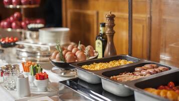Ein reichhaltiges Buffet mit verschiedenen Speisen, darunter Eier, Würstchen und Gemüse.