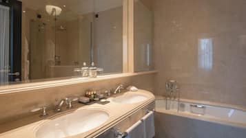 A modern bathroom with two sinks, a large mirror, and a bathtub.