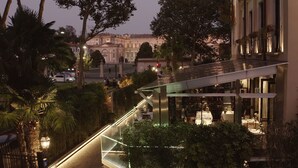 Un hotel moderno con un puente de cristal que conecta dos edificios, rodeado de exuberante vegetación y palmeras.