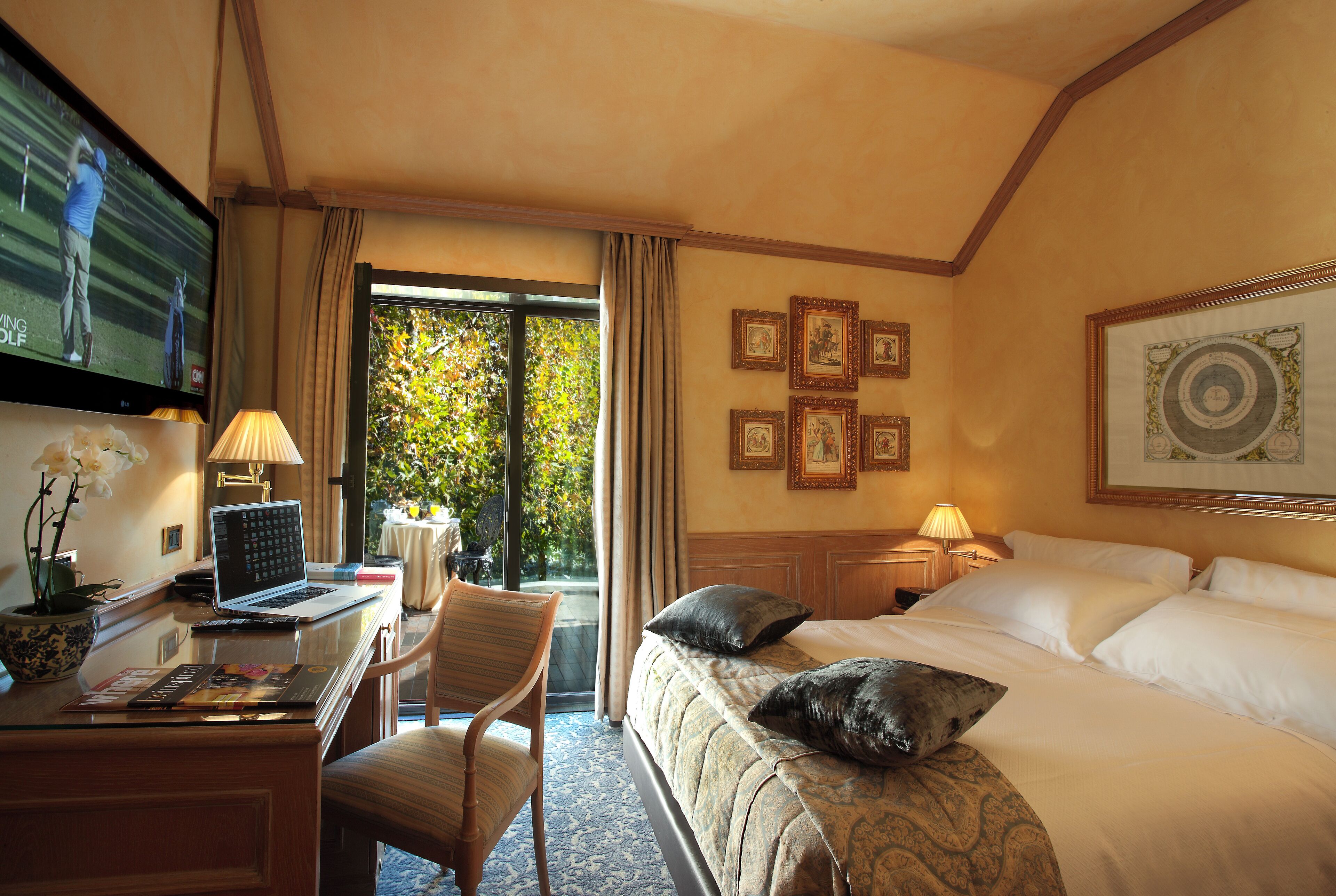 Ein Hotelzimmer mit Bett, Schreibtisch, Laptop, Stuhl und Fernseher.