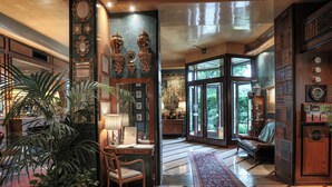 A spacious lobby with a large wooden bench, a potted plant, and a red patterned rug.