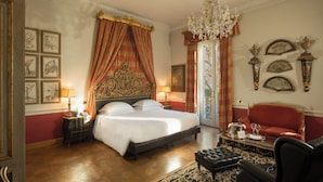 A spacious bedroom with a large bed, a chandelier, and a red sofa.