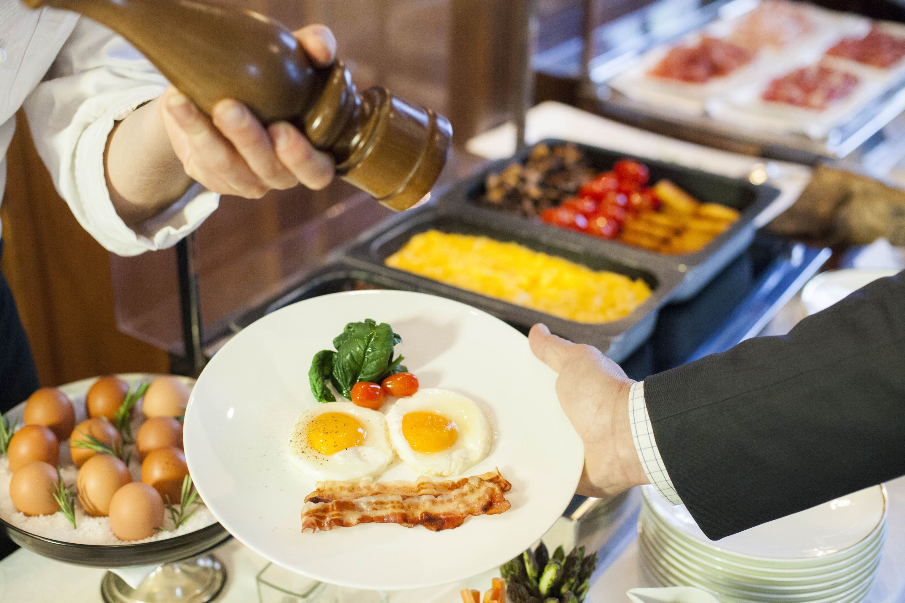 Montaje de bufé con diversos alimentos, incluyendo huevos, tocino y vegetales.