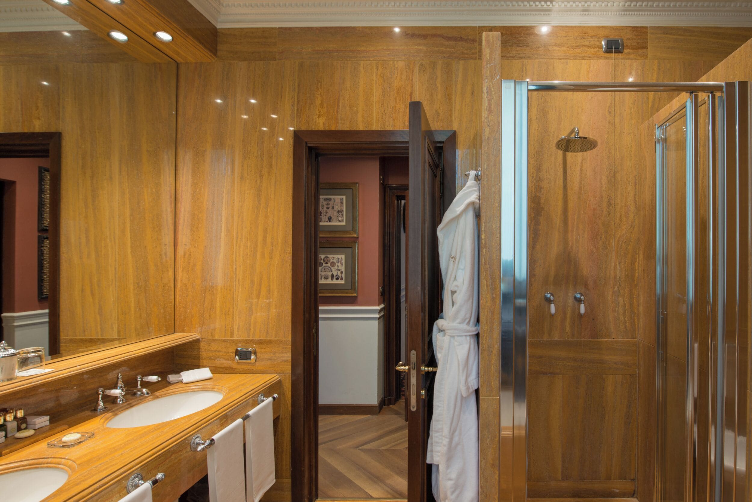 Un baño lujoso con paneles de madera, un espejo grande, dos lavamanos y una ducha a ras de suelo.