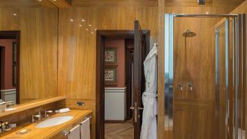 Un baño lujoso con paneles de madera, un espejo grande, dos lavamanos y una ducha a ras de suelo.