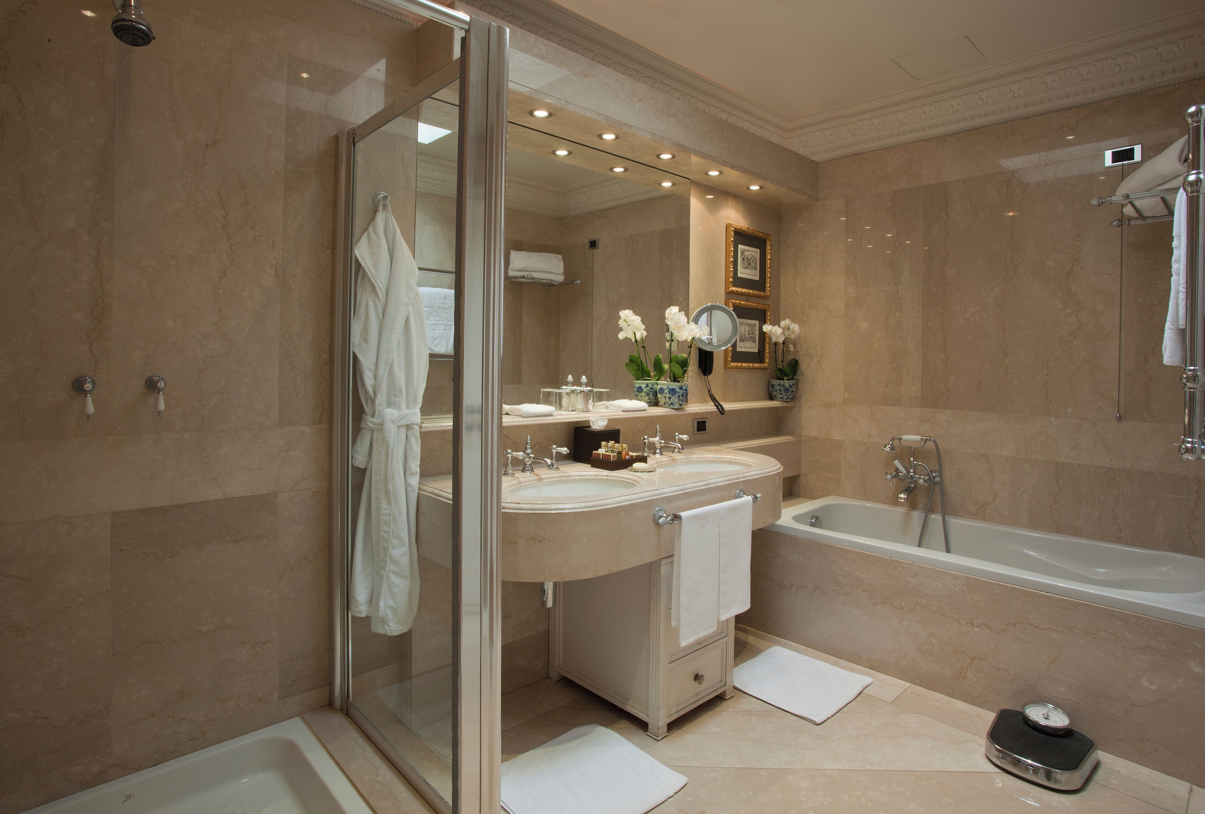 Een moderne badkamer met een douchecabine van glas, dubbele wastafels, een badkuip en een wastafelmeubel met spiegel.