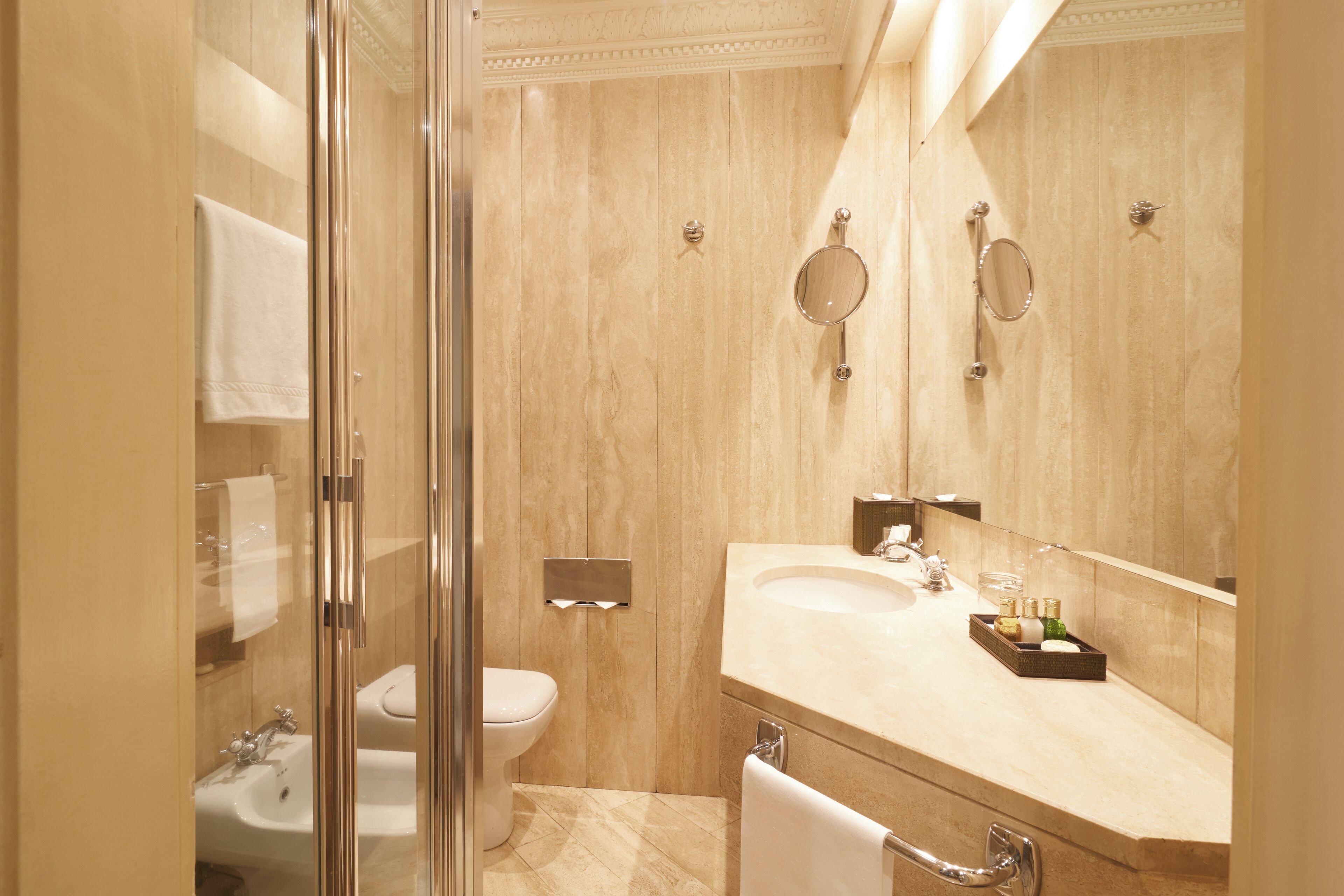 A modern bathroom with a glass shower enclosure, a white toilet, a sink, and a vanity with a mirror.