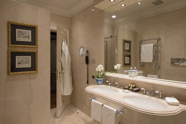 A luxurious bathroom with a large mirror, double sink, and a robe rack.