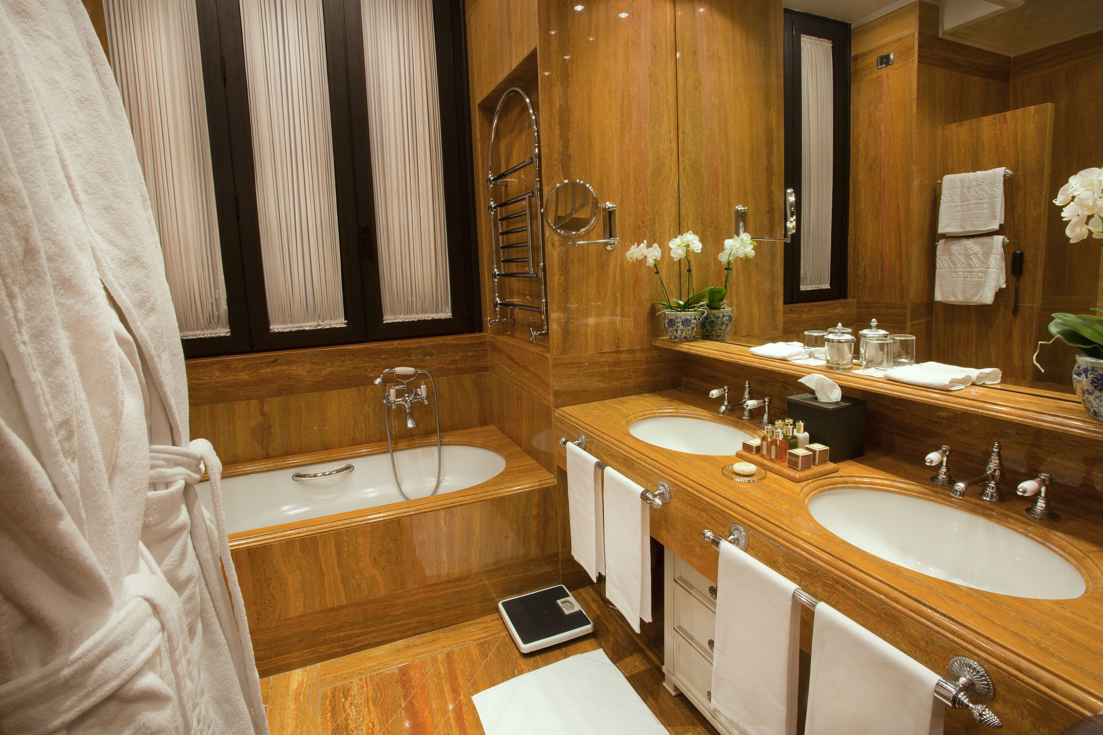 Un baño lujoso con lavamanos doble, una bañera y un espejo grande.