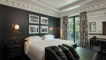 Habitación de hotel con una cama grande, un escritorio y vistas a zonas verdes por la ventana.
