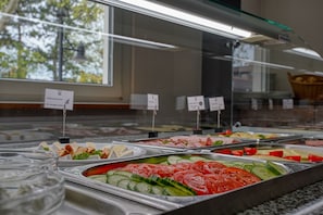 Un bufé con diversas opciones de comida, incluyendo pepinos en rodajas, tomates y queso.