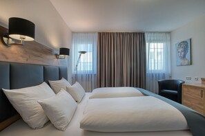 Habitación de hotel con una cama grande, dos mesitas de noche, un escritorio, una silla y un cuadro en la pared.