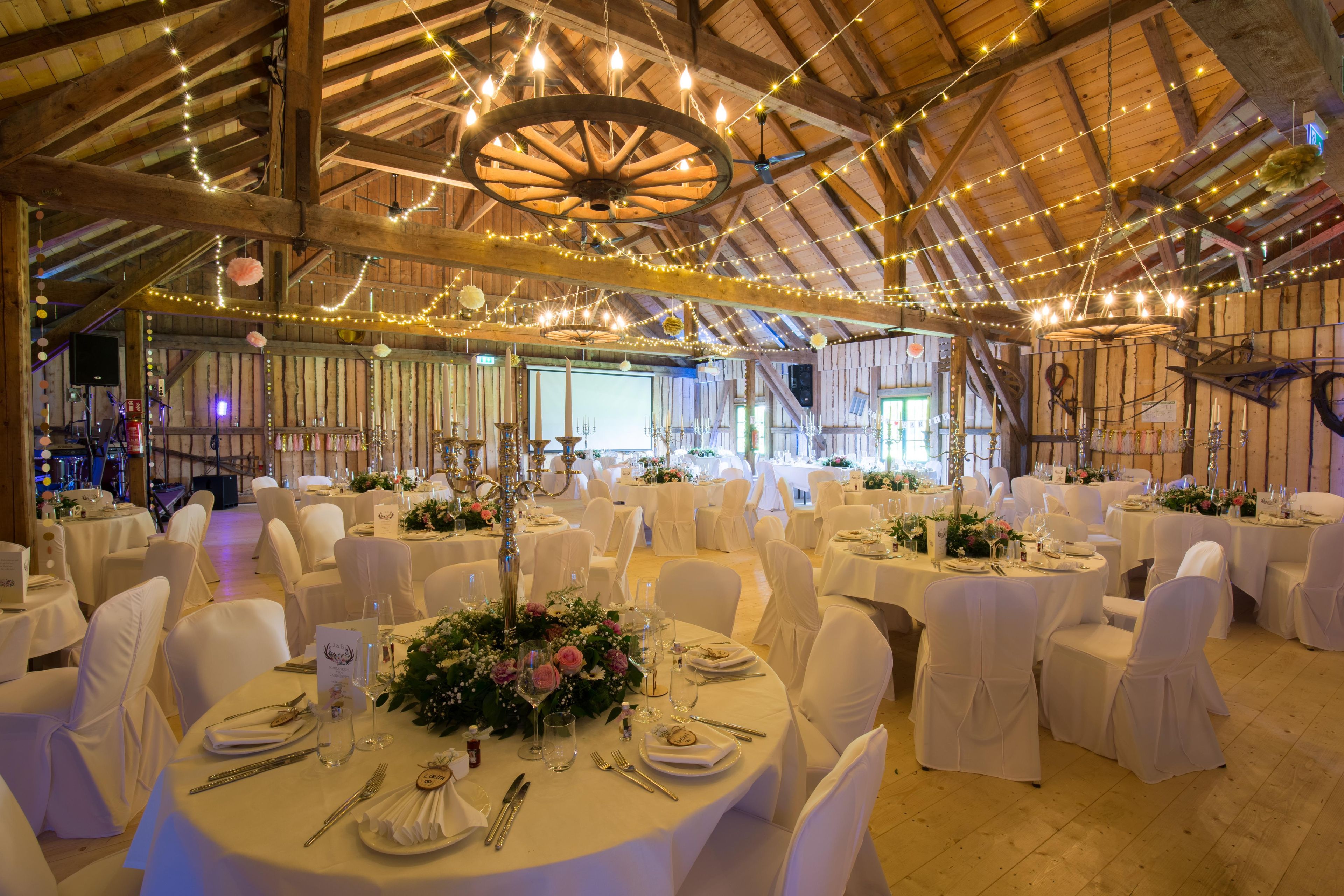 A banquet hall with round tables, white tablecloths, and candle centerpieces.