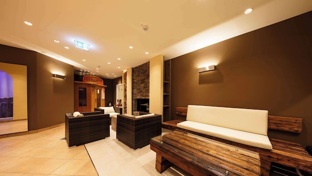 A modern spa area with a reception desk, seating area, and a stone wall. - Hotel Bayerischer Hof Miesbach, BW Premier Collection (Miesbach)