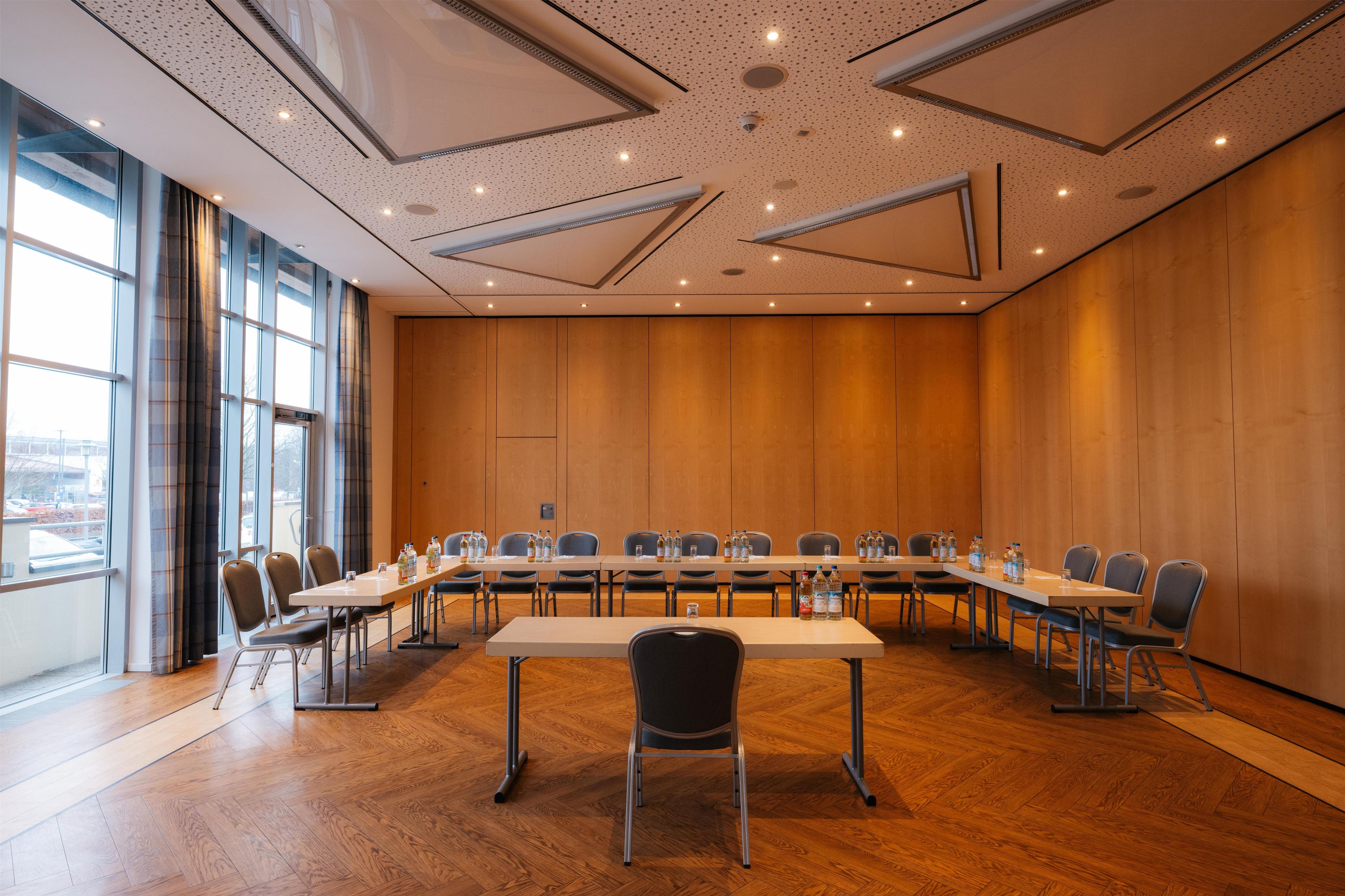 Una sala de conferencias con una larga mesa, sillas y vistas a la ciudad a través de amplios ventanales.