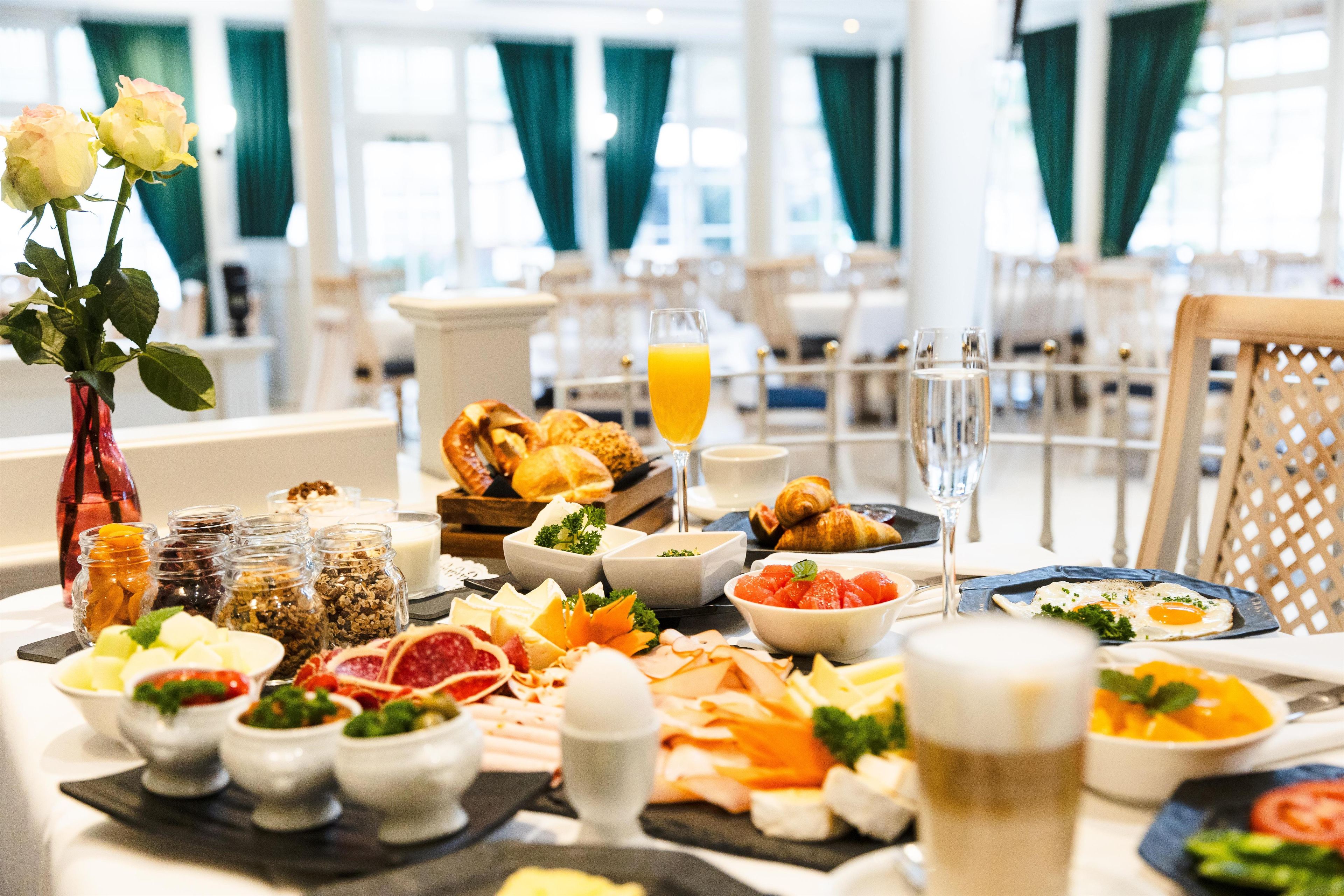 Ein reichhaltiges Frühstücksbuffet mit Speisen und einer Blumenvase.