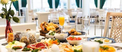 Un bufé de desayuno con diversos alimentos y un jarrón de flores.
