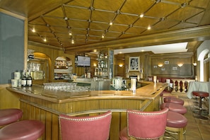 A bar area with wooden bar counter, multiple stools, and a variety of bottles and glasses. - Hotel Bayerischer Hof Miesbach, BW Premier Collection (Miesbach)